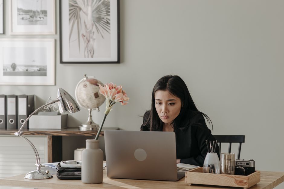 Mulher concentrada trabalhando em um escritório moderno, demonstrando foco e produtividade no ambiente de trabalho.