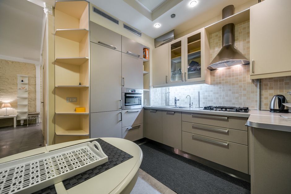 Cozinha moderna e bem iluminada, com destaque para móveis planejados, cooktop e eletrodomésticos, ideal para artigos sobre organização e design de cozinhas.