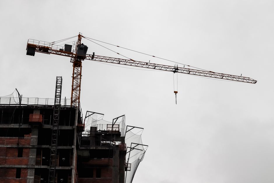 Imagem de uma construção em andamento com uma torre de guindaste contra um céu nublado, representando o tema de construção civil e desenvolvimento urbano.