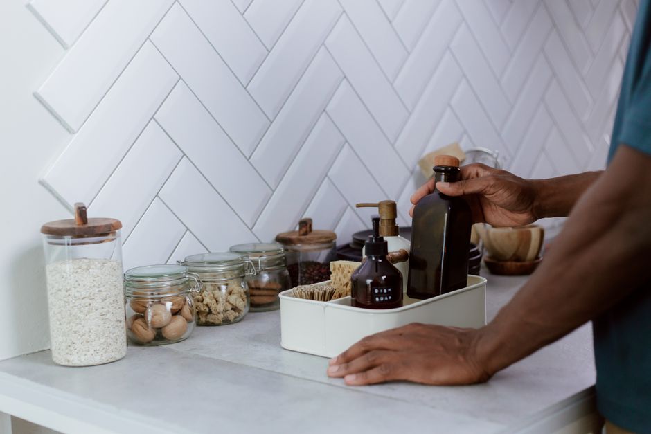 Pessoa organizando itens na cozinha, destacando a rotina de armazenamento de alimentos naturais e utensílios domésticos.