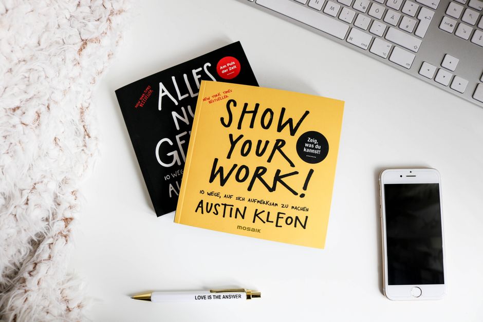 Imagem de uma mesa de trabalho com livros, celular, teclado e caneta, ideal para artigos sobre produtividade e organização pessoal.