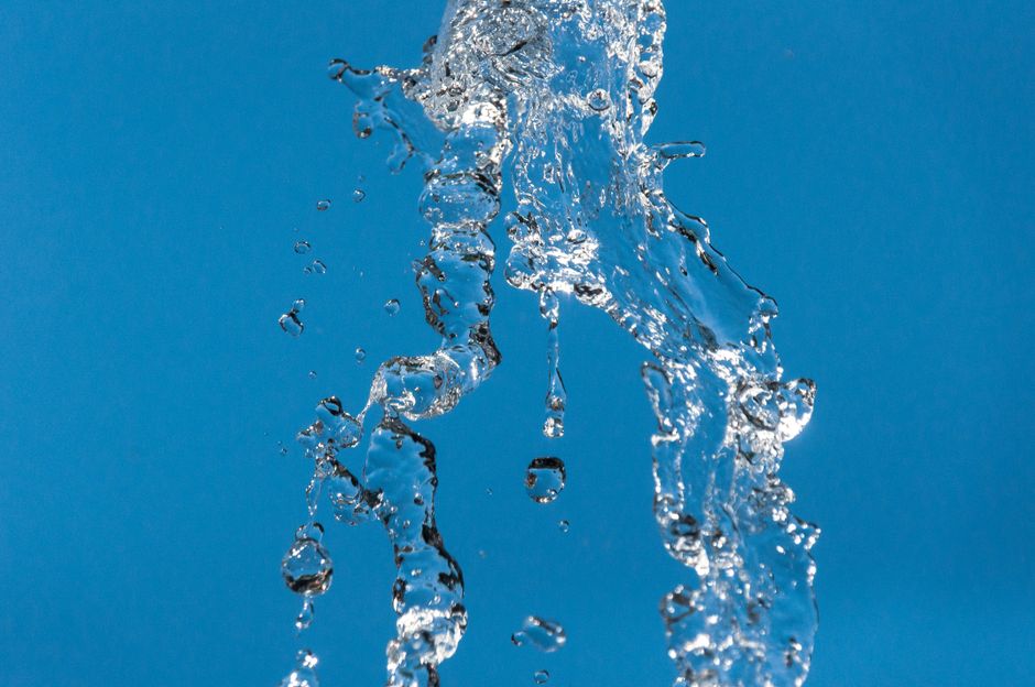 Imagem de água cristalina caindo contra um fundo azul, simbolizando limpeza, renovação ou pureza.