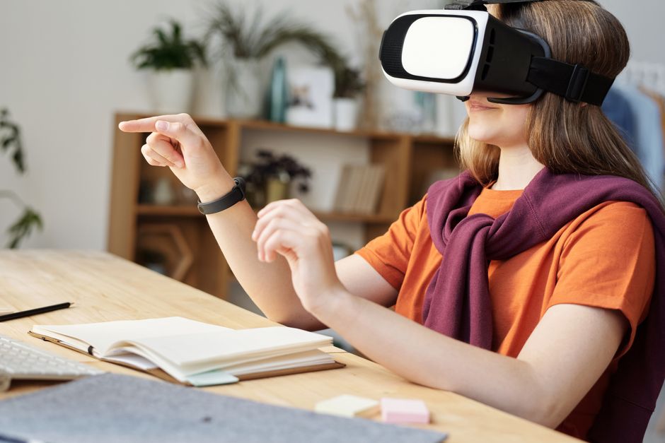 Pessoa usando óculos de realidade virtual em ambiente de trabalho ou estudo, explorando novas tecnologias.