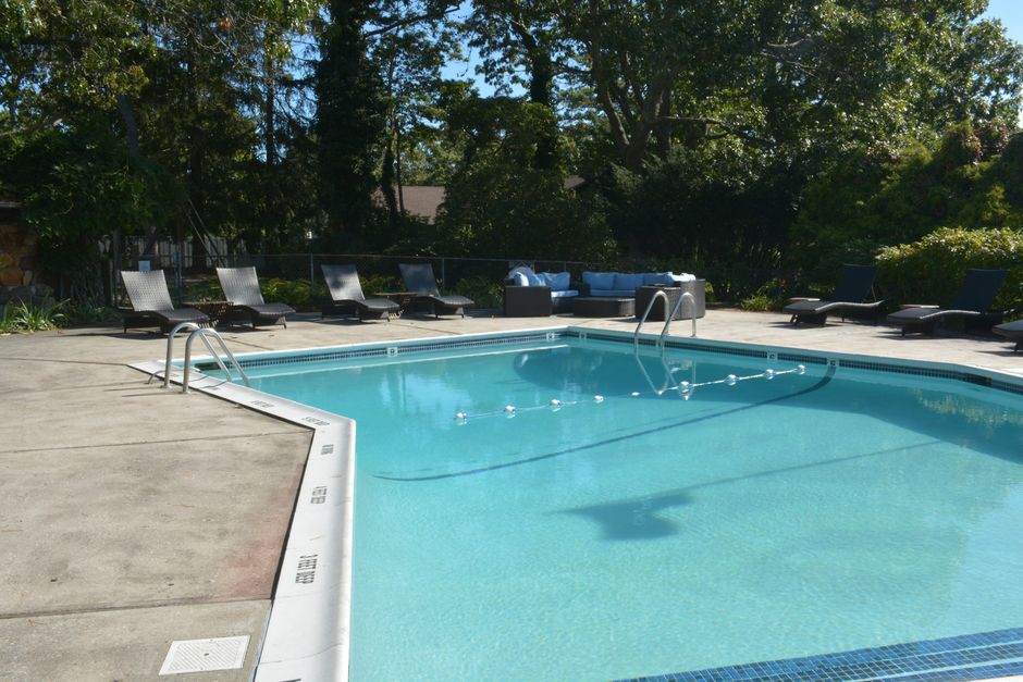 Imagem de uma piscina ao ar livre cercada por espreguiçadeiras e áreas de convivência, em um ambiente de lazer e descanso na natureza.