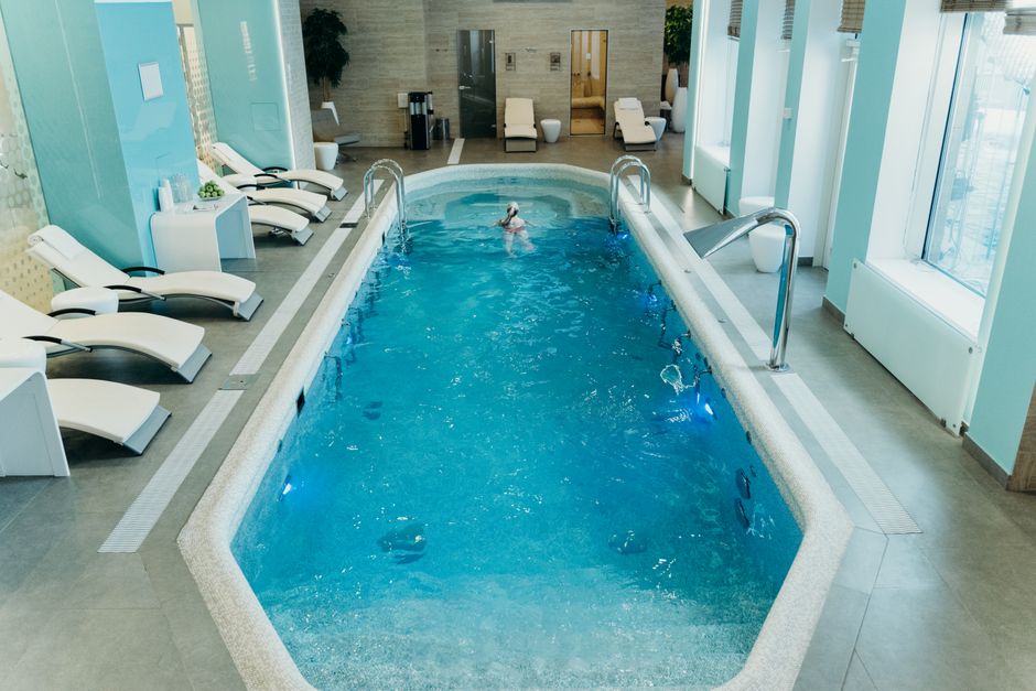 Interior de um spa com piscina aquecida, área de relaxamento e cadeiras de massagem, ideal para momentos de descanso e bem-estar.