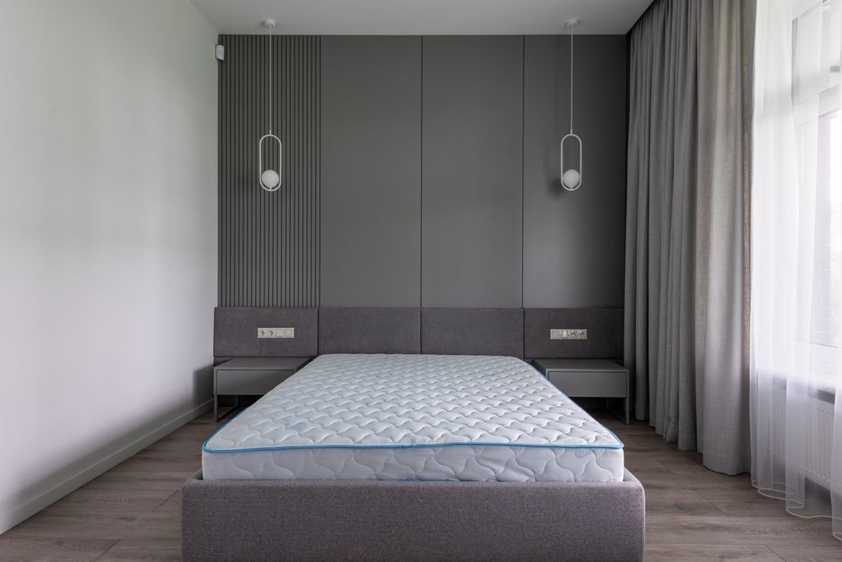 Quarto minimalista com cabeceira revestida e iluminação moderna, ideal para decoração contemporânea e ambientes sugerindo conforto e sofisticação.