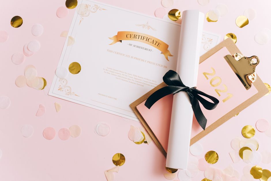 Imagem de um diploma de conquista, comemorando o final de um ciclo acadêmico ou profissional, rodeado de confetes dourados e um calendário de 2021, simbolizando celebração e realizações.