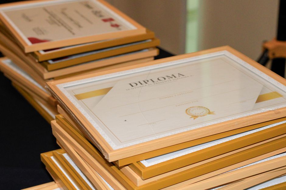 Vários diplomas empilhados, prontos para serem entregues a formandos, representando celebração e conquista acadêmica.