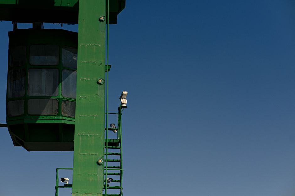 Estrutura de cabina de observação ou controle com escadas e câmeras sob um céu azul claro, simbolizando vigilância ou monitoramento externo.
