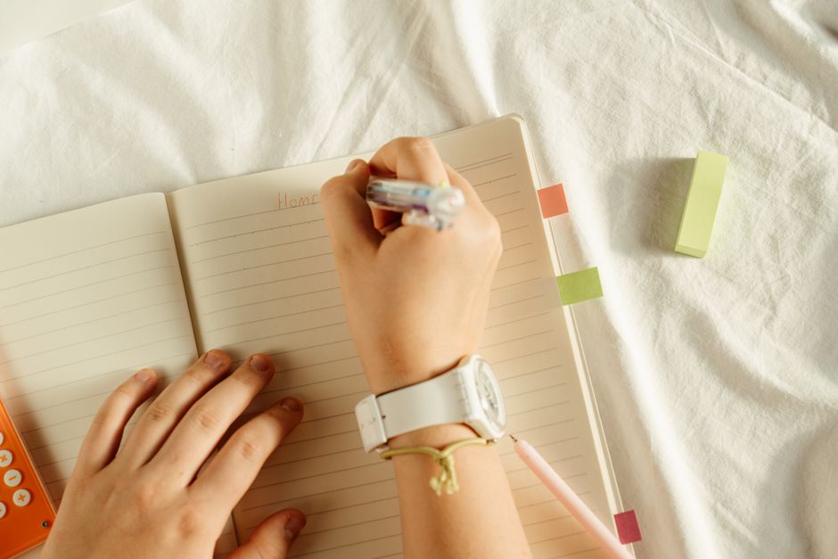 Pessoa escrevendo em um caderno, simbolizando planejamento, organização ou tomada de notas para um artigo de blog sobre produtividade ou gestão de tarefas.