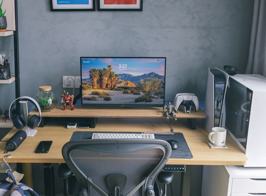 Estação de trabalho de um gamer ou criador de conteúdo com computador, headset, controle de videogame e outros acessórios em um ambiente moderno.