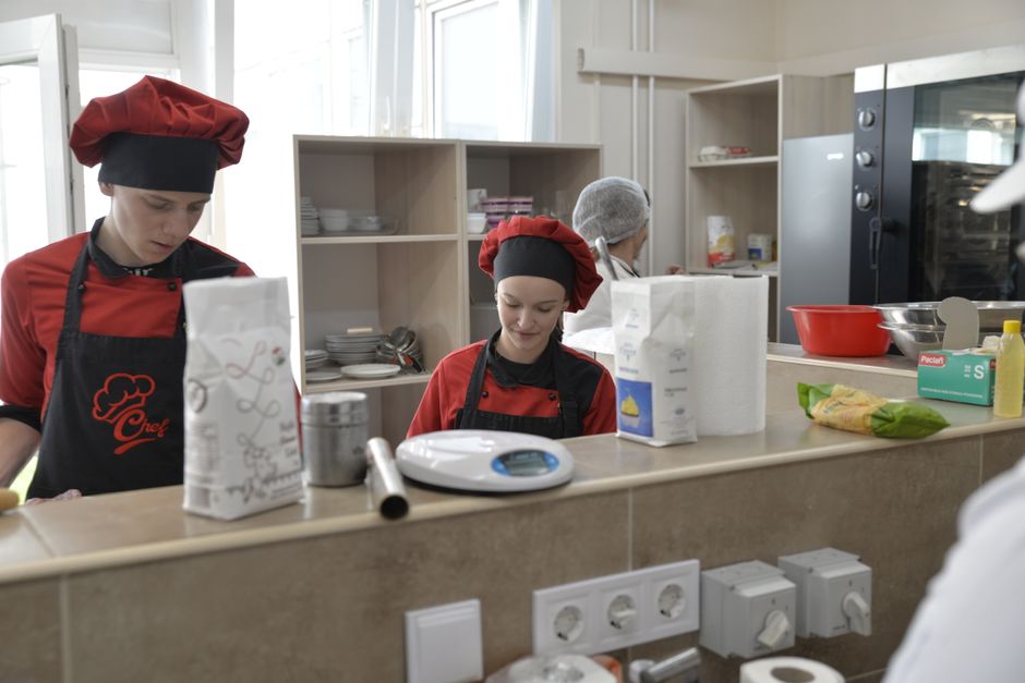 Jovens chefs em aula de culinária, preparando pratos em uma cozinha ensinando técnicas gastronômicas.