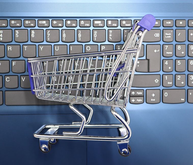 Carrinho de compras sobre um teclado de computador simbolizando compras online ou comércio eletrônico.