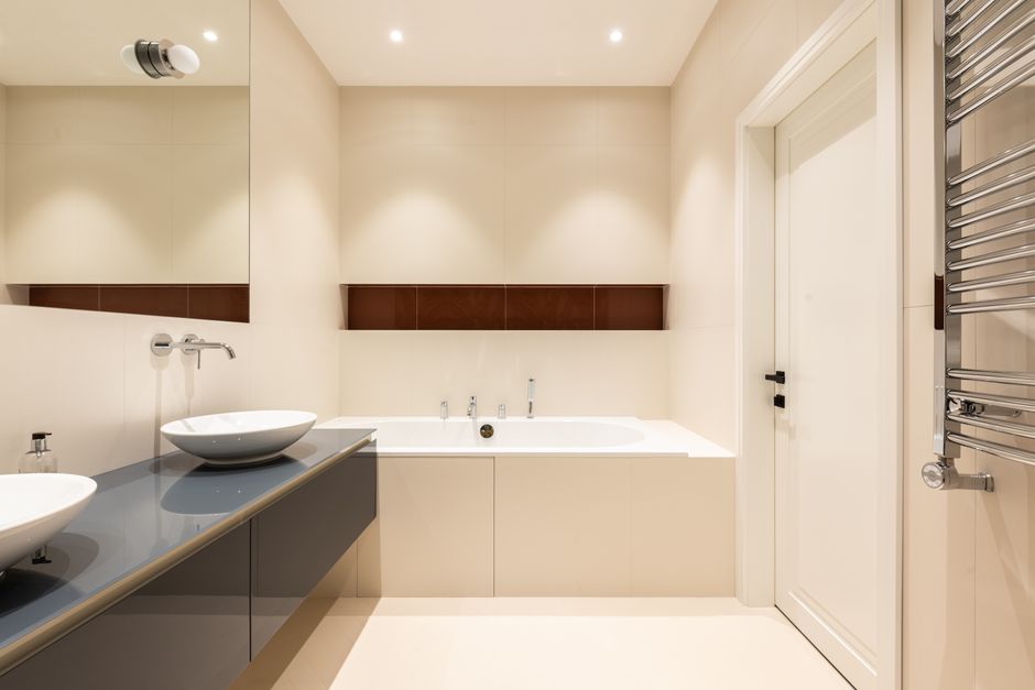 Imagem de um banheiro moderno com detalhes minimalistas, incluindo banheira, espelhos e torneiras elegantes.