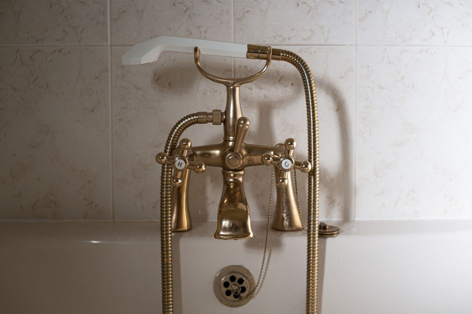 Imagem de uma banheira com uma torneira de design clássico, destacando-se pelo acabamento dourado e detalhes vintage, ideal para ilustrar decoração de banheiro ou estilo retrô.
