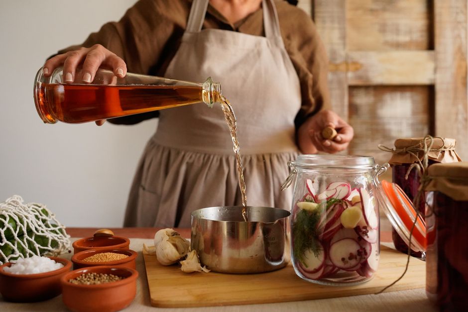 Pessoa preparando um conservas caseiro com ingredientes naturais em uma cozinha rústica.