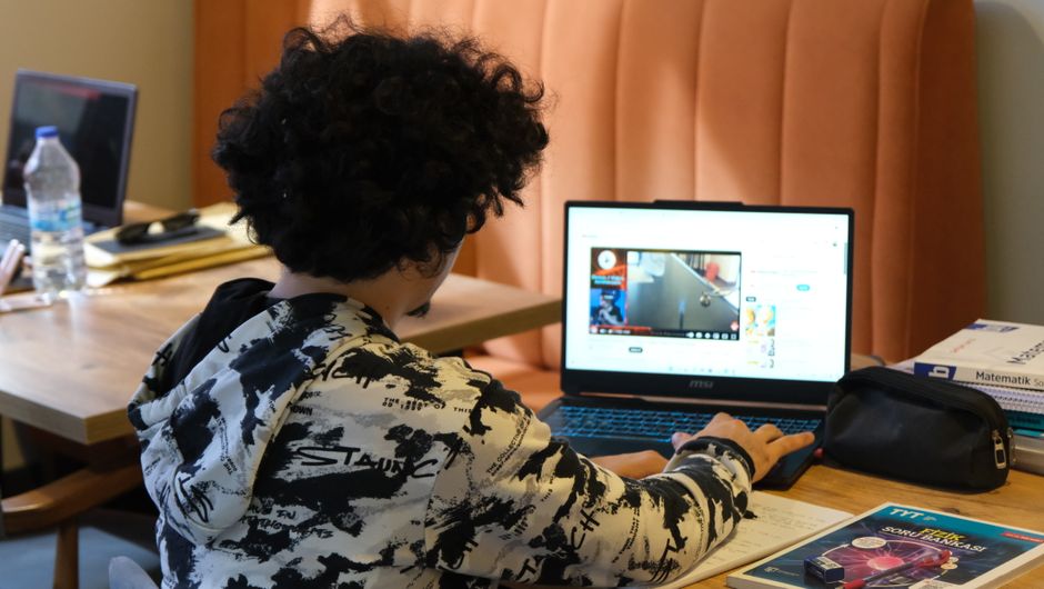 Criança assistindo aula online ou vídeo educativo em um ambiente de estudo ou sala de aula.