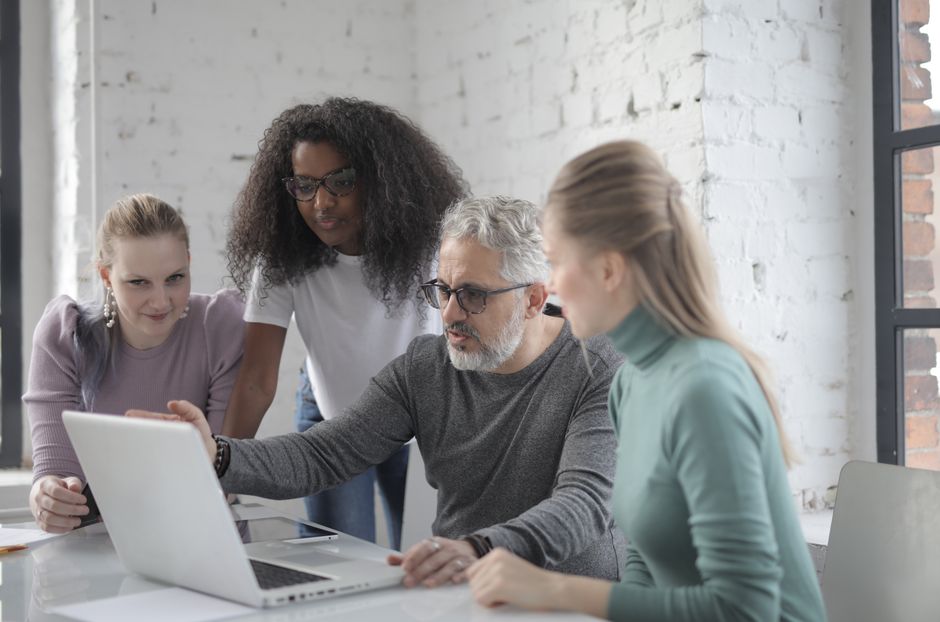 Grupo de colegas de trabalho colaborando em uma reunião de planejamento ou discussão de projeto em ambiente de escritório moderno.