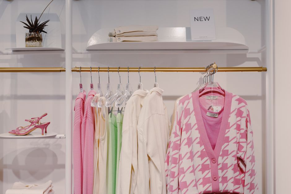 Vitrine de loja de roupas apresentando diferentes peças de vestuário e acessórios em um ambiente bem iluminado e organizado.