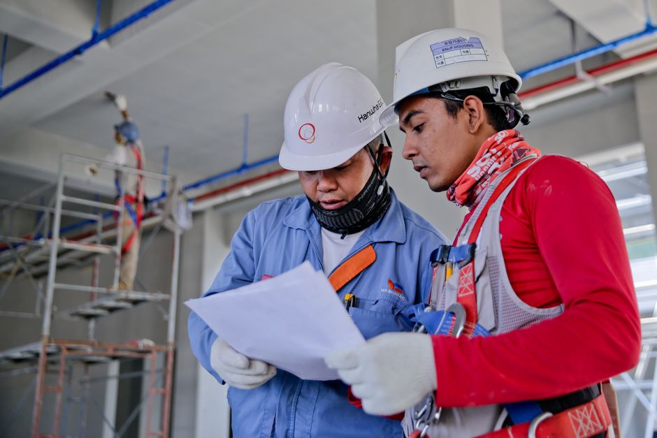 Engenheiros analisando projetos em uma obra de construção civil, destacando planejamento e supervisão técnica.
