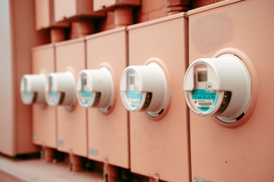 Imagem de medidores de energia elétrica instalados em um painel, representando temas relacionados à gestão de recursos e consumo energético.