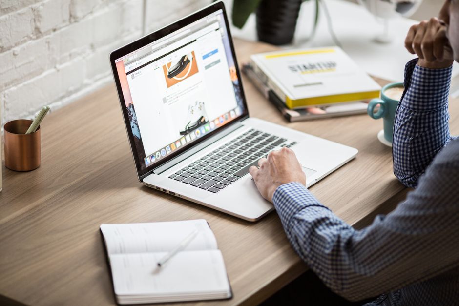 Pessoa analisando produtos em um site de comércio eletrônico em ambiente de trabalho moderno.