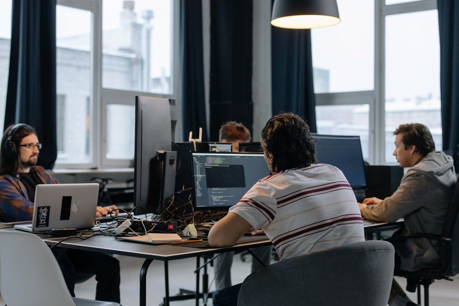 Grupo de profissionais trabalhando em um escritório de tecnologia, focado em desenvolvimento de software e inovação.