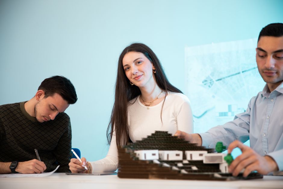 Grupo de jovens profissionais trabalhando em um projeto de modelagem ou design inovador em um ambiente de escritório criativo.