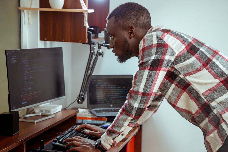 Homem concentrado trabalhando com programação em um ambiente de escritório doméstico ou de tecnologia.