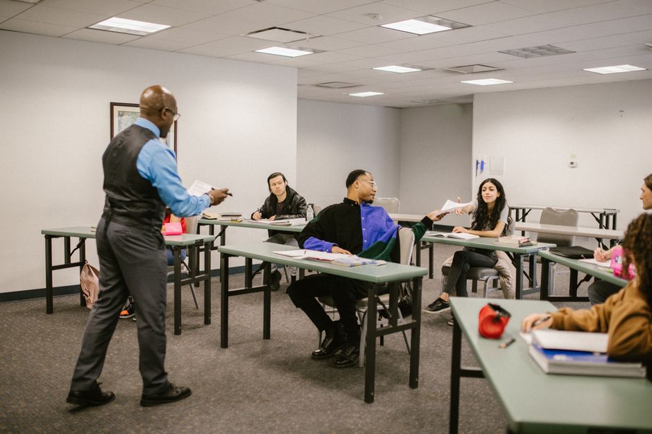 Homem conduzindo uma aula ou reunião com estudantes em um ambiente de ensino ou capacitação.