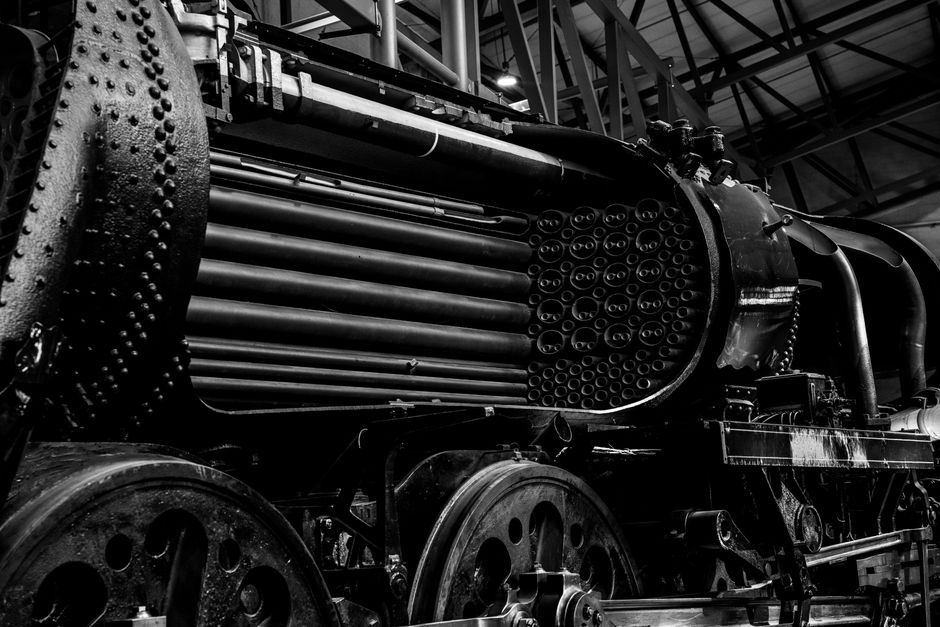 Imagem em preto e branco de uma máquina industrial exposta em um ambiente industrial, destacando suas características técnicas e estrutura robusta.
