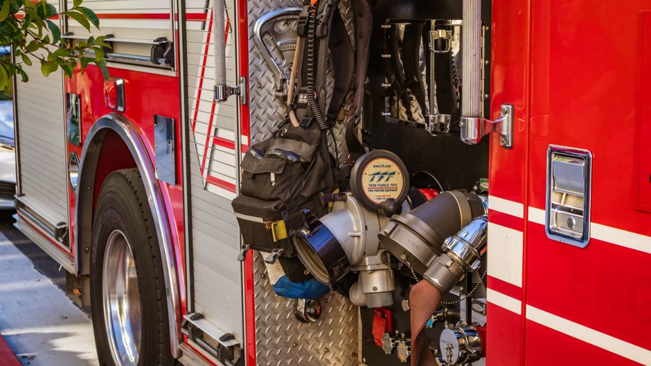 Imagem de um caminhão de bombeiros equipado com mangueiras, equipamentos de proteção e ferramentas de combate a incêndio, pronto para agir em uma emergência.