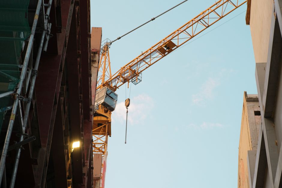 Foto de uma área de construção civil com uma grua em funcionamento, destacando o ambiente de obras e edificações em desenvolvimento.