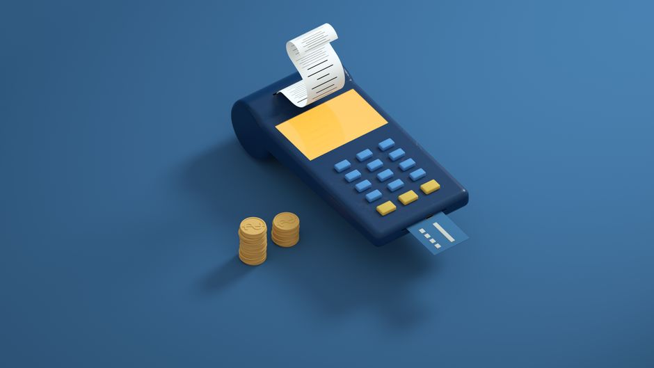 Imagem ilustrativa de uma calculadora de chão, com um recibo saindo e alguns moedas, representando temas de finanças e controle financeiro.