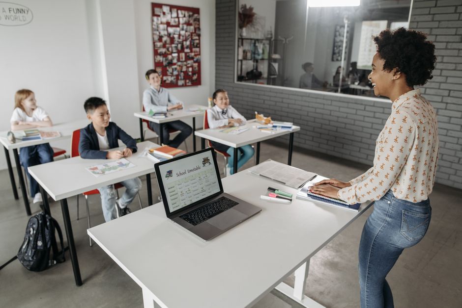 Professora ensinando uma turma de crianças em uma sala de aula com ênfase no ambiente educacional e na interação pedagógica.