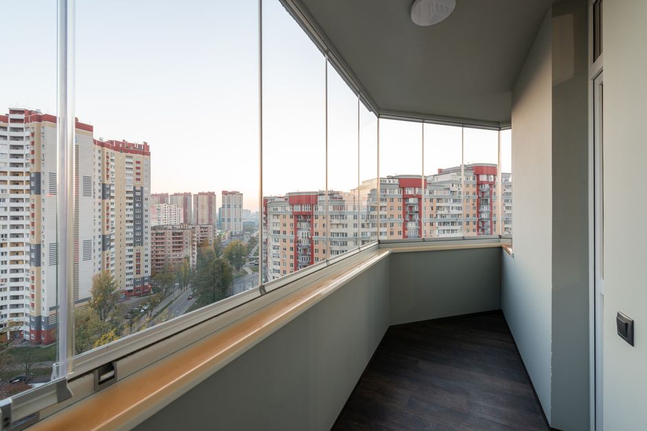 Visão de uma varanda em um prédio residencial com vista para uma região urbana repleta de edifícios altos e árvores, sugerindo um ambiente de moradia em meio à cidade.