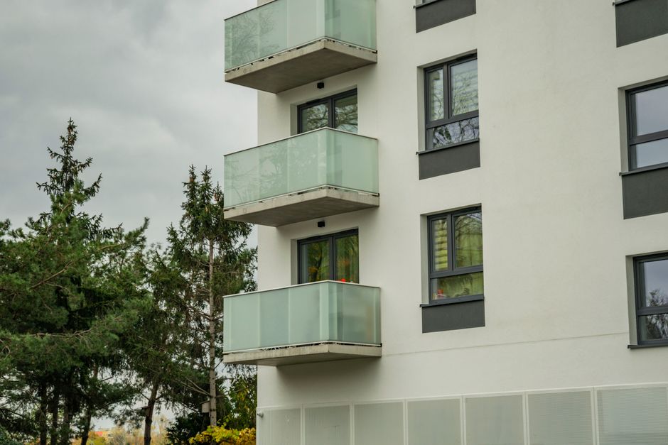 Imagem de um prédio residencial com balcões de vidro, destacando o aspecto arquitetônico moderno e urbano.