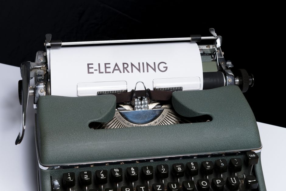 Imagem de uma máquina de escrever com uma folha de papel escrita 'E-LEARNING', simbolizando o ensino digital e remoto.
