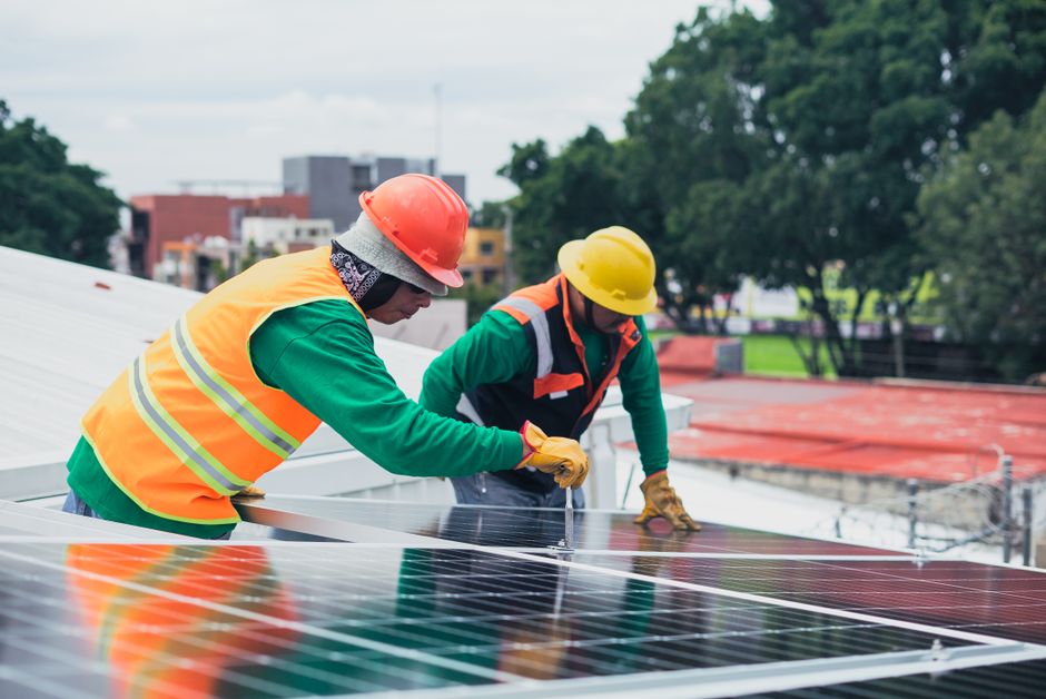 Trabalhadores instalando painéis solares em uma cobertura urbana, demonstrando energia renovável e sustentabilidade.
