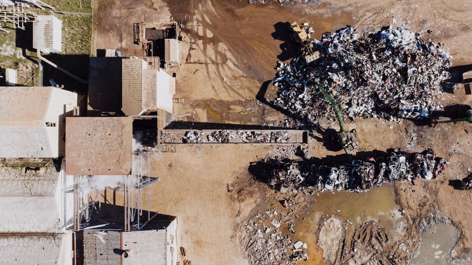 Imagem aérea de um aterro sanitário, mostrando descarte de resíduos sólidos em um espaço ao ar livre.