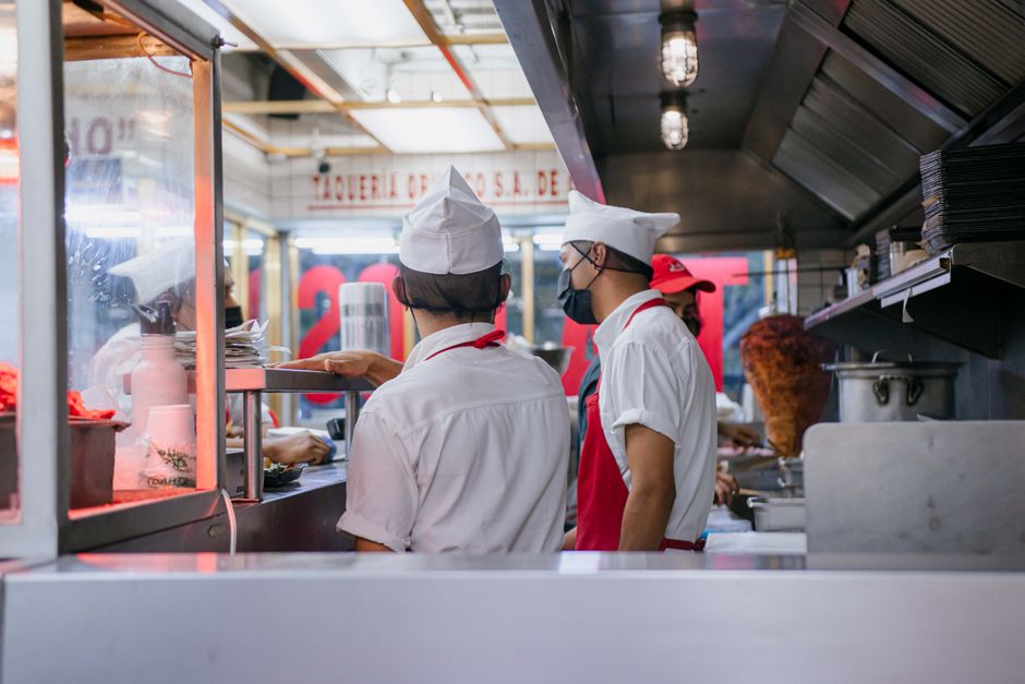 Equipe de cozinheiros trabalhando na preparação de alimentos em uma cozinha de restaurante, com foco na rotina gastronômica e atendimento ao cliente.