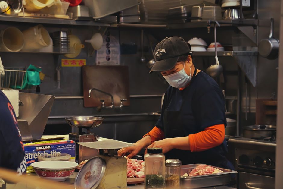 Chef preparando ingredientes na cozinha de um restaurante, com atenção aos detalhes na preparação dos alimentos.