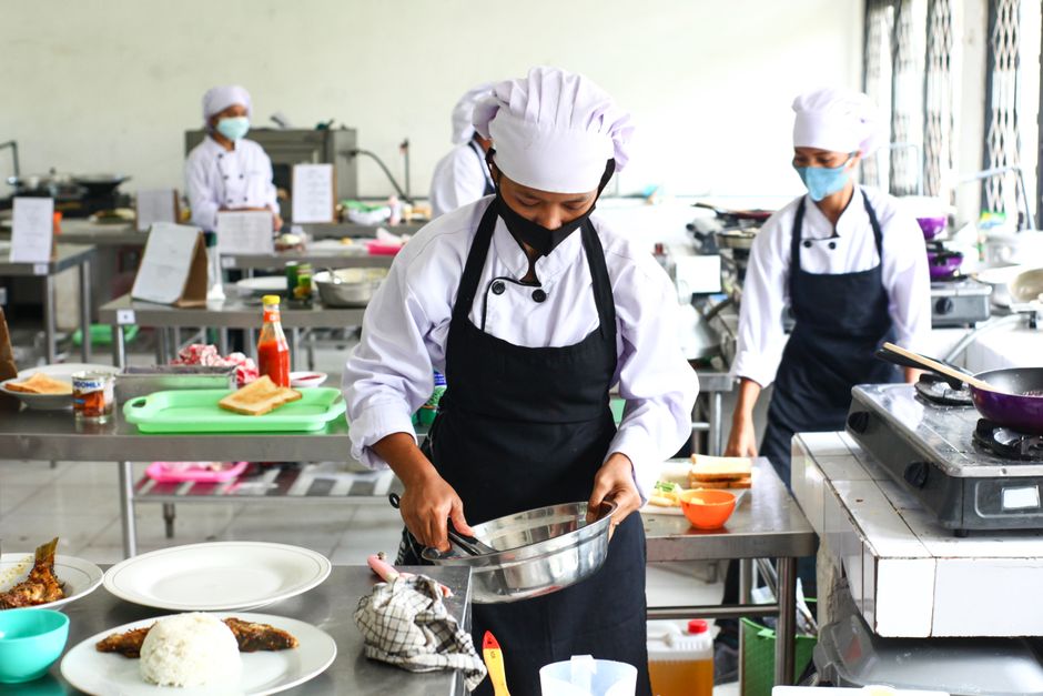 Equipe de cozinheiros preparando pratos em uma cozinha profissional com foco na produção culinária.