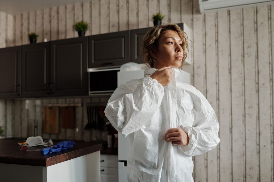 Mulher se preparando para entrar em ação durante uma rotina de análise de riscos ou emergência doméstica, em ambiente de cozinha com estilo rústico.
