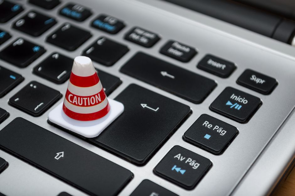 Imagem de um teclado de computador com uma pequena cone de advertência com a mensagem 'Caution' destacando a importância da segurança digital.