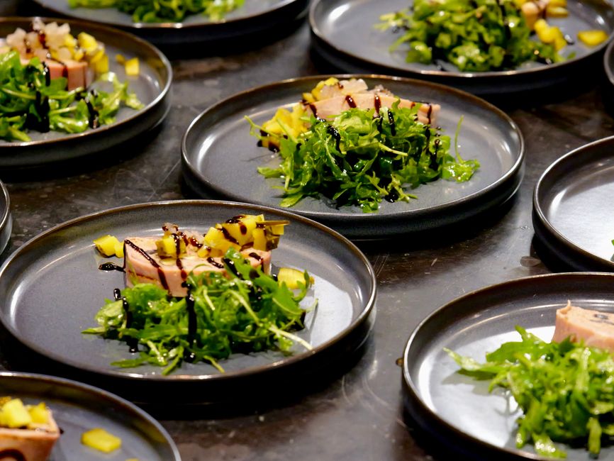 Pratos de salada gourmet apresentados em uma linha de montagem, destacando a preparação de alimentos sofisticados e artesanais.