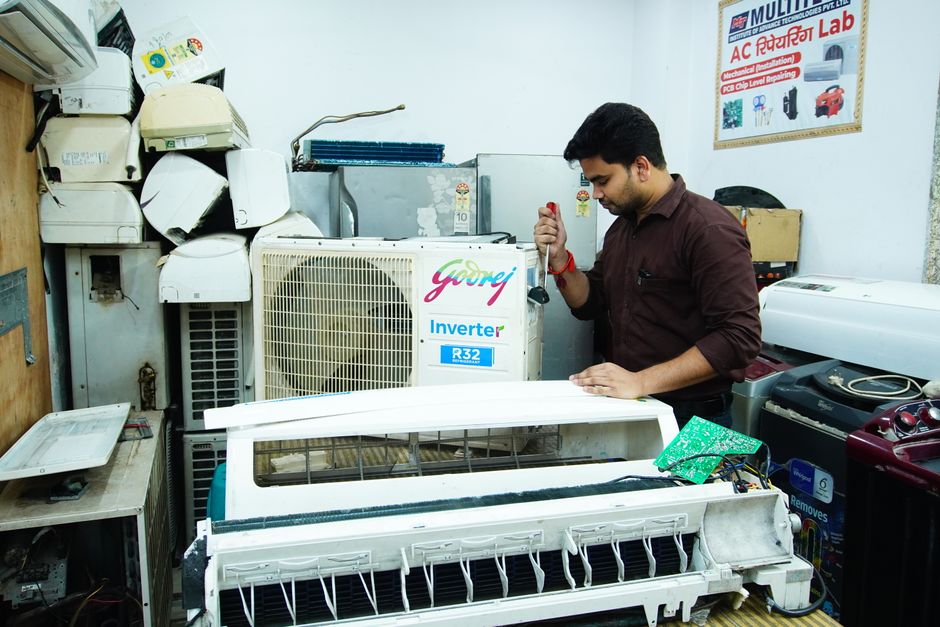 Técnico realizando manutenção em um aparelho de ar condicionado em uma oficina especializada.