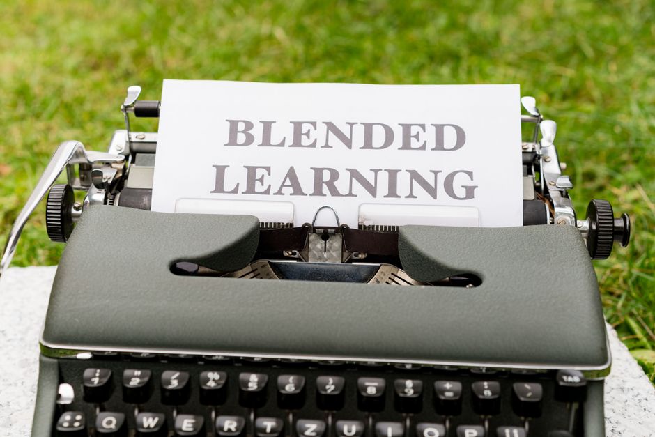Máquina de escrever com uma folha de papel que exibe o texto 'Blended Learning', simbolizando a combinação de métodos de ensino tradicionais e tecnológicos.