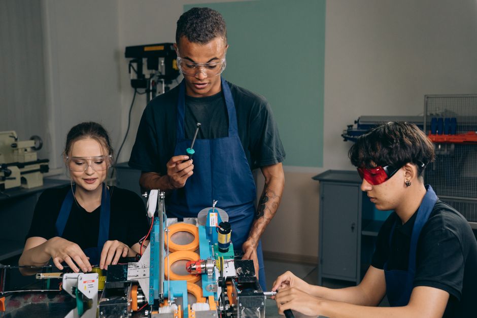 Grupo de jovens engenheiros e estudantes envolvidos em um projeto de robótica em laboratório educacional.