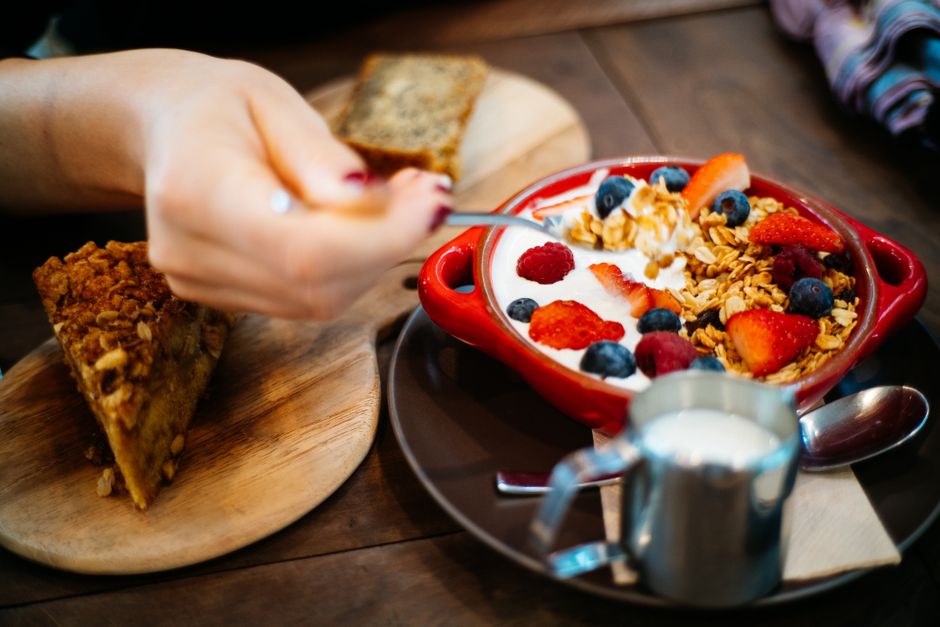 Imagem de um café da manhã saudável com iogurte, frutas vermelhas e granola, ideal para artigos sobre alimentação balanceada e rotina matinal.
